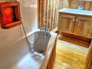 Experience rustic charm in this bathroom featuring a classic clawfoot tub and a wooden vanity with a light blue sink.
