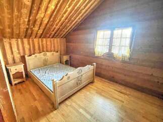 Experience rustic charm in this cozy bedroom featuring a beautifully crafted wooden bed with intricate carvings.
