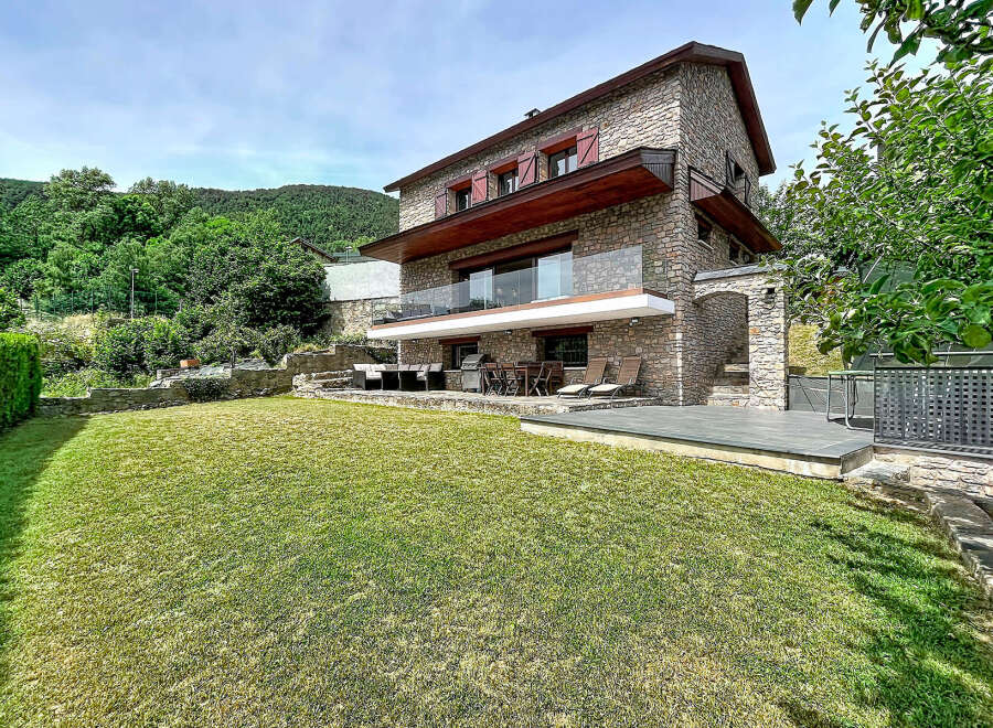 Discover this stunning stone house nestled in a serene, green landscape.