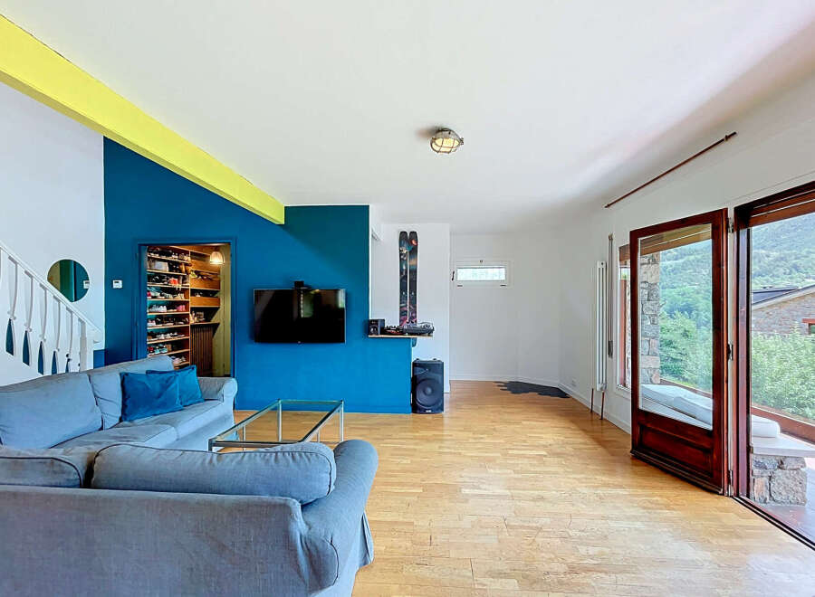 Discover this spacious living area featuring a comfortable blue sectional sofa and a modern entertainment setup with a wall-mounted TV.