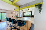 Experience modern industrial living in this stunning kitchen featuring vibrant lime green beams and exposed concrete accents.