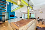 Discover this unique open-plan living space featuring a striking industrial-style kitchen island with a butcher block countertop.