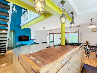 Discover this unique open-plan living space featuring a striking industrial-style kitchen island with a butcher block countertop.