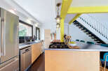 This modern kitchen features a sleek stainless steel refrigerator and dishwasher, complemented by light wood cabinetry and a durable metal countertop.