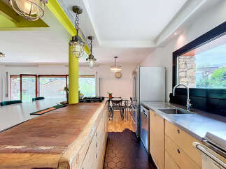 Experience modern living in this spacious kitchen featuring a large wooden island, sleek stainless steel countertops, and a professional gas range.
