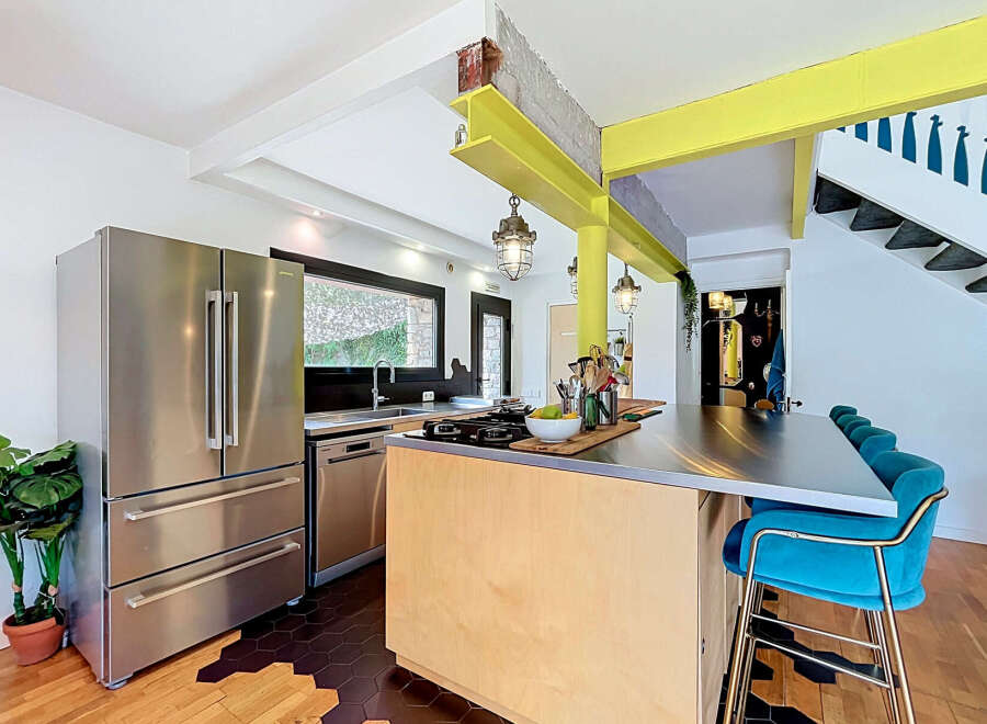 This modern kitchen boasts a sleek stainless steel refrigerator and dishwasher, complemented by a spacious island with a metallic countertop.