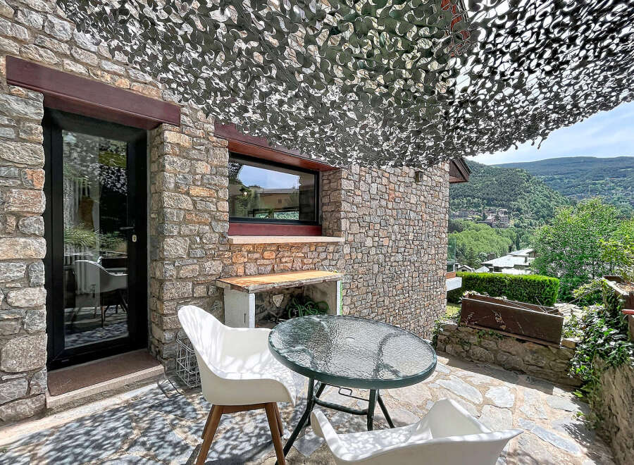 Enjoy outdoor living on this charming stone patio, complete with a glass-top table and comfortable white chairs.
