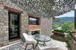 Enjoy outdoor living on this charming stone patio, complete with a glass-top table and comfortable white chairs.