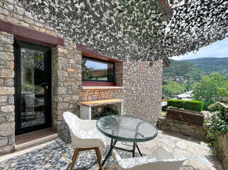 Enjoy outdoor living on this charming stone patio, complete with a glass-top table and comfortable white chairs.