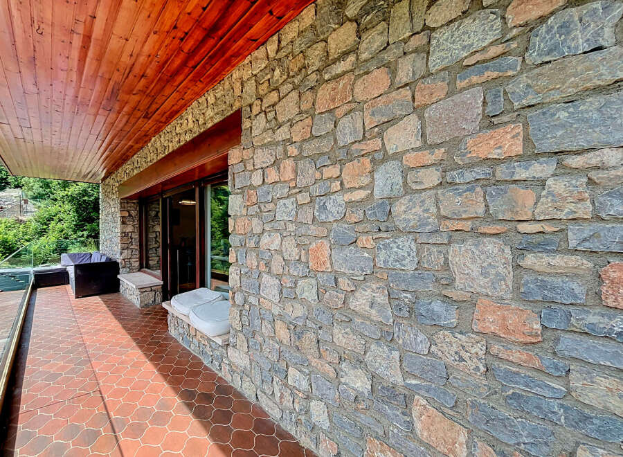 Experience the charm of this rustic property featuring a beautiful stone facade and a warm wooden ceiling on the covered patio.