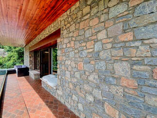 Experience the charm of this rustic property featuring a beautiful stone facade and a warm wooden ceiling on the covered patio.