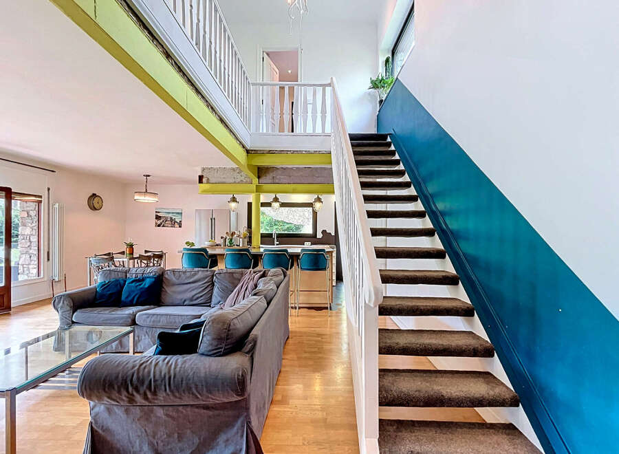 Experience modern living in this spacious open-concept home, featuring a stylish living area with a plush sectional sofa and a sleek glass coffee table.