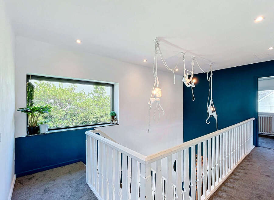 This modern hallway features a striking dark blue accent wall that beautifully contrasts with the crisp white walls and ceiling.