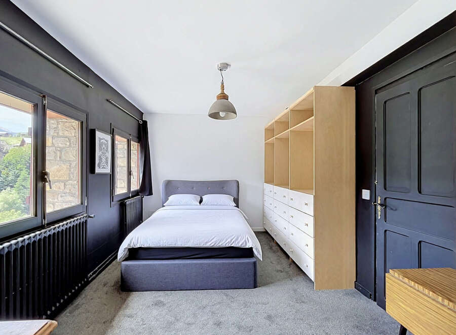 Discover this charming bedroom featuring a comfortable bed with a grey upholstered headboard, perfect for relaxation.