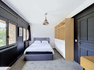 Discover this charming bedroom featuring a comfortable bed with a grey upholstered headboard, perfect for relaxation.