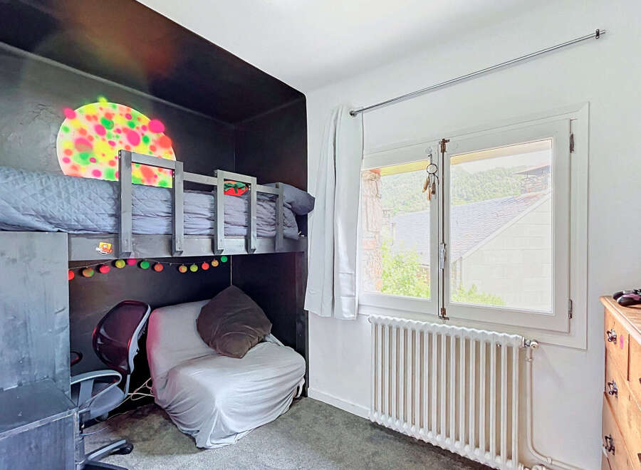 This unique bedroom features a loft bed with a playful, colorful mural above it, creating a vibrant and imaginative space.