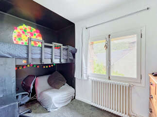 This unique bedroom features a loft bed with a playful, colorful mural above it, creating a vibrant and imaginative space.