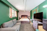 Discover this charming studio apartment featuring a comfortable queen-size bed with a tufted headboard and plush bedding.