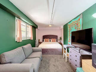 Discover this charming studio apartment featuring a comfortable queen-size bed with a tufted headboard and plush bedding.