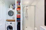 This compact bathroom maximizes space with a stacked Bosch washer and dryer, perfect for smaller homes or apartments.