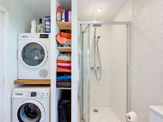 This compact bathroom maximizes space with a stacked Bosch washer and dryer, perfect for smaller homes or apartments.