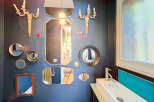 This eclectic bathroom features a striking gallery wall adorned with an assortment of decorative mirrors and vintage sconces, creating a unique focal point.