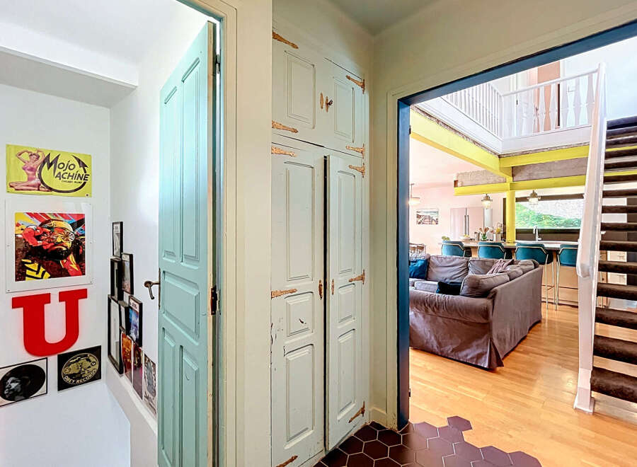 Step into this charming home featuring a unique teal door and a striking built-in cabinet with antique hardware.