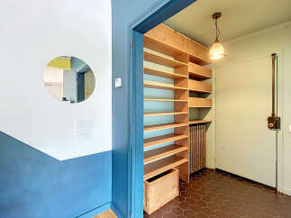 Discover this charming entryway featuring a unique circular mirror and a striking blue and white accent wall.