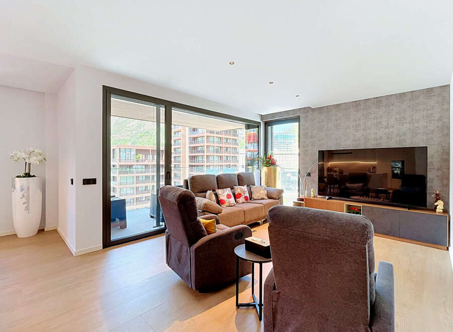 Experience modern living in this spacious apartment featuring a comfortable living area with plush recliners and a sofa, perfect for relaxation.
