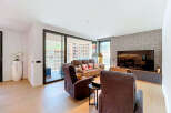 Experience modern living in this spacious apartment featuring a comfortable living area with plush recliners and a sofa, perfect for relaxation.