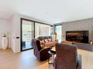 Experience modern living in this spacious apartment featuring a comfortable living area with plush recliners and a sofa, perfect for relaxation.