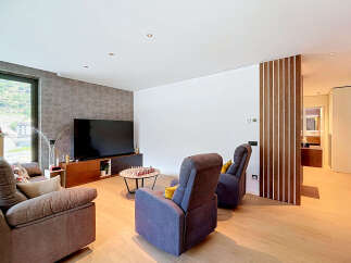 Experience modern living in this spacious living room, featuring a large flat-screen TV, comfortable seating, and a stylish coffee table with a chess set.