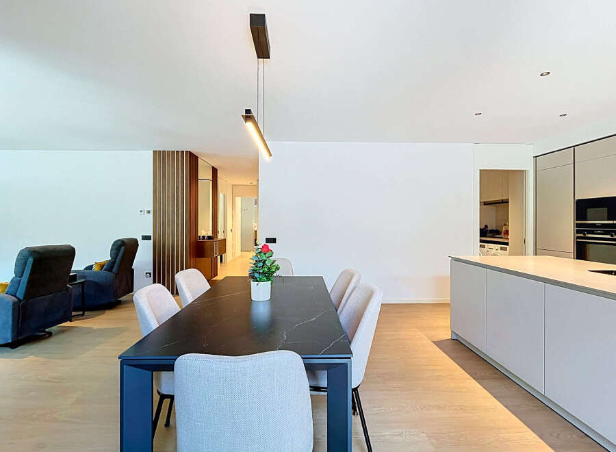 Experience modern living in this open-concept space featuring a sleek dining area with a marble-top table and comfortable upholstered chairs.