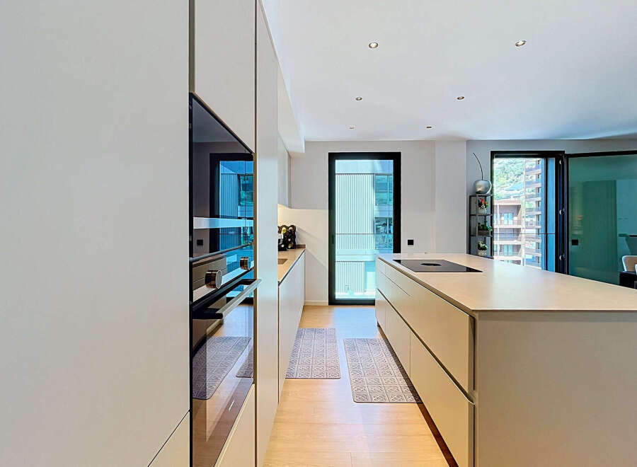 Experience modern luxury in this stunning kitchen featuring sleek, integrated appliances and a spacious island with a built-in cooktop.