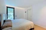 Experience modern comfort in this beautifully appointed bedroom, featuring a plush bed with elegant pillows and a large window offering stunning city and mountain views.