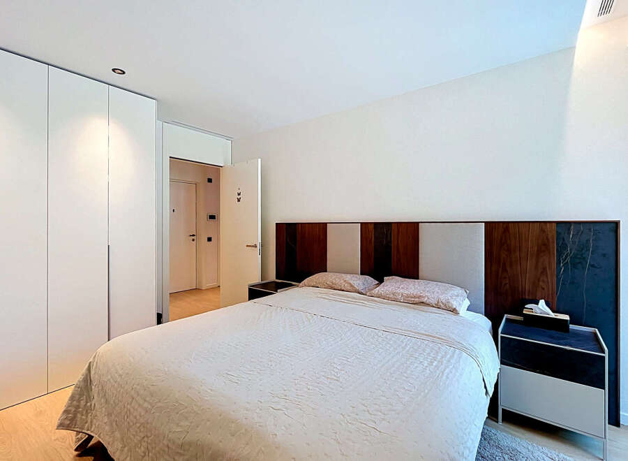 Experience modern comfort in this elegantly designed bedroom, featuring a spacious bed with a striking, multi-textured headboard.