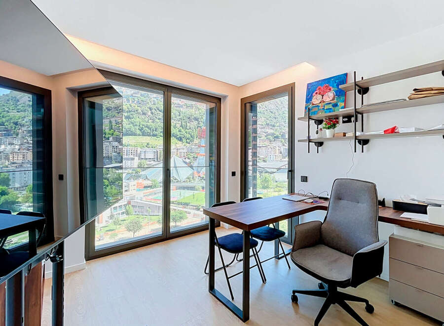 Experience breathtaking mountain and city views from this modern home office, featuring expansive windows that flood the space with natural light.