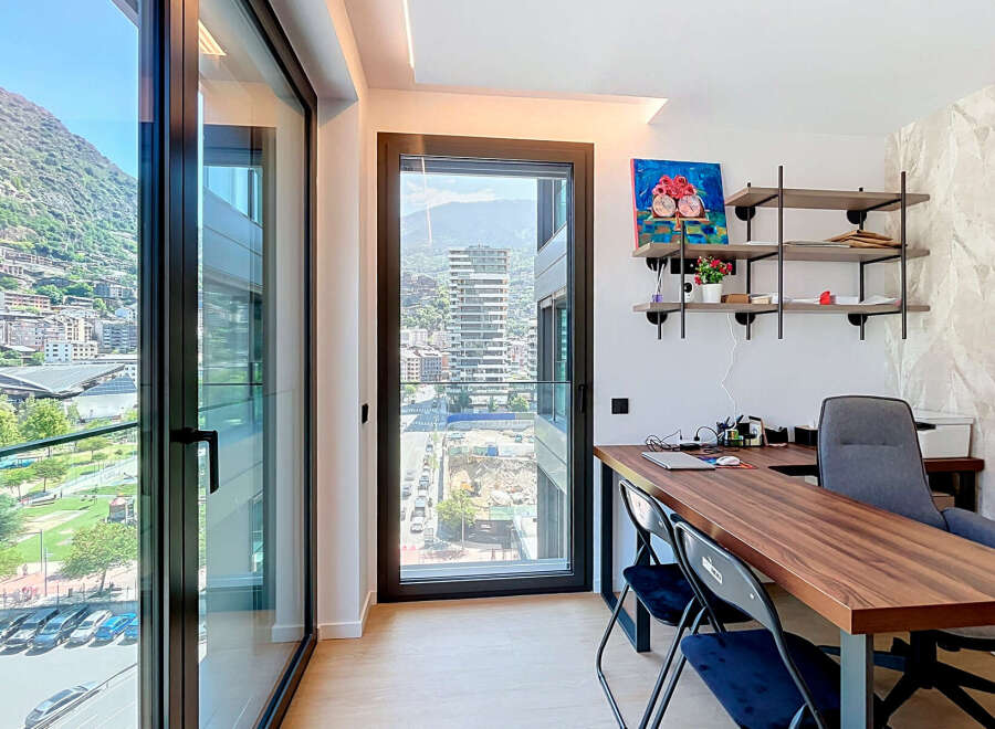 Experience modern living with this stunning home office featuring expansive floor-to-ceiling windows that offer breathtaking mountain and city views.