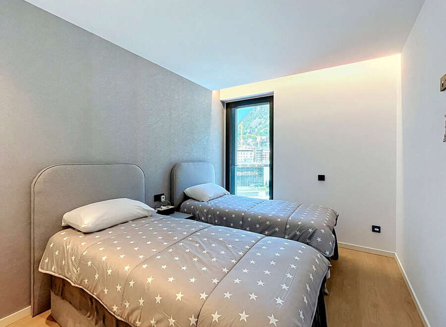 This modern bedroom features two comfortable twin beds with stylish grey headboards and star-patterned comforters.