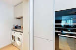 Discover this modern laundry room featuring stacked white appliances, including a washer and dryer, complemented by ample cabinet storage above.