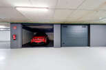 Discover this modern underground parking space featuring a sleek red electric vehicle.
