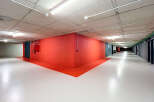 Discover this modern and well-lit underground parking space, featuring a striking red accent wall and a clean, white epoxy floor.