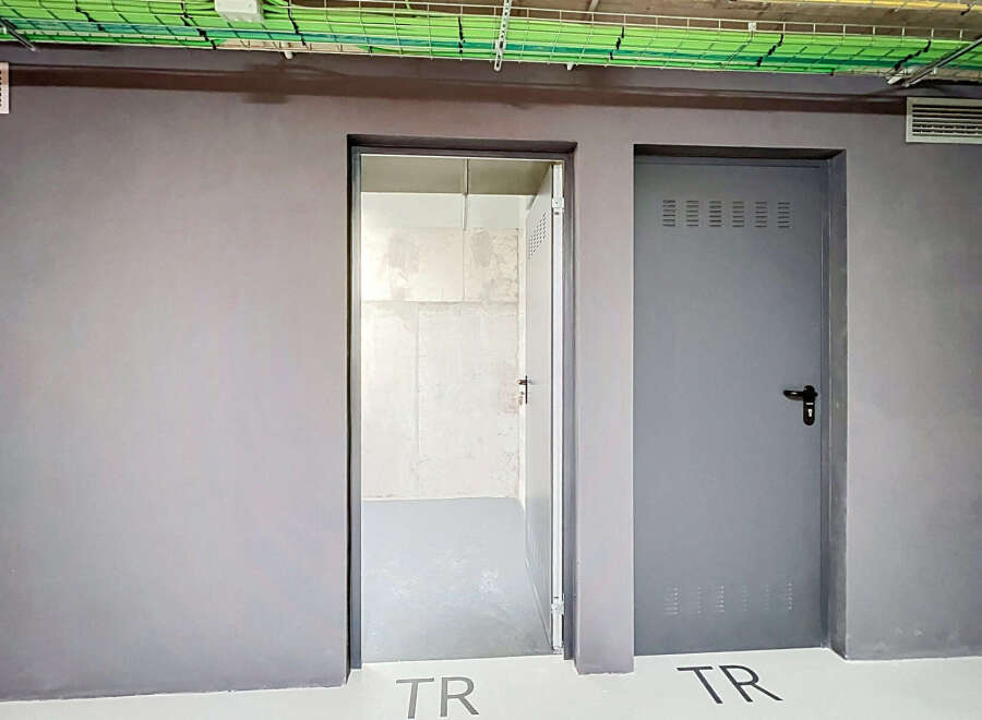 Discover modern functionality with two distinct doors, one open to reveal a clean, unfinished interior, and the other a closed grey metal door with ventilation slots.