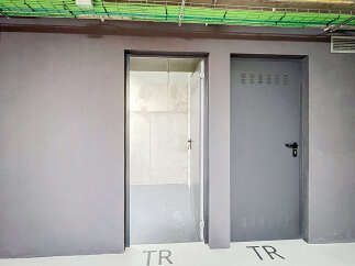 Discover modern functionality with two distinct doors, one open to reveal a clean, unfinished interior, and the other a closed grey metal door with ventilation slots.