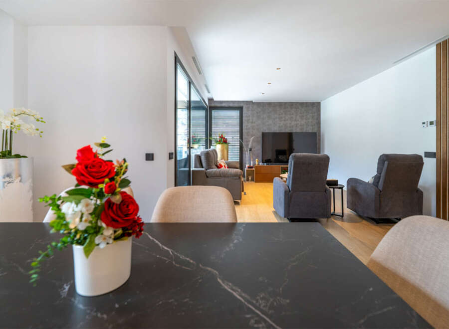 Experience modern living in this spacious open-plan home, featuring a sleek dining area with a marble-top table and a comfortable living room.