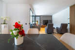 Experience modern living in this spacious open-plan home, featuring a sleek dining area with a marble-top table and a comfortable living room.