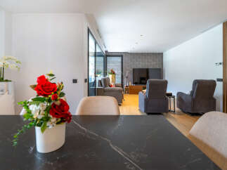 Experience modern living in this spacious open-plan home, featuring a sleek dining area with a marble-top table and a comfortable living room.
