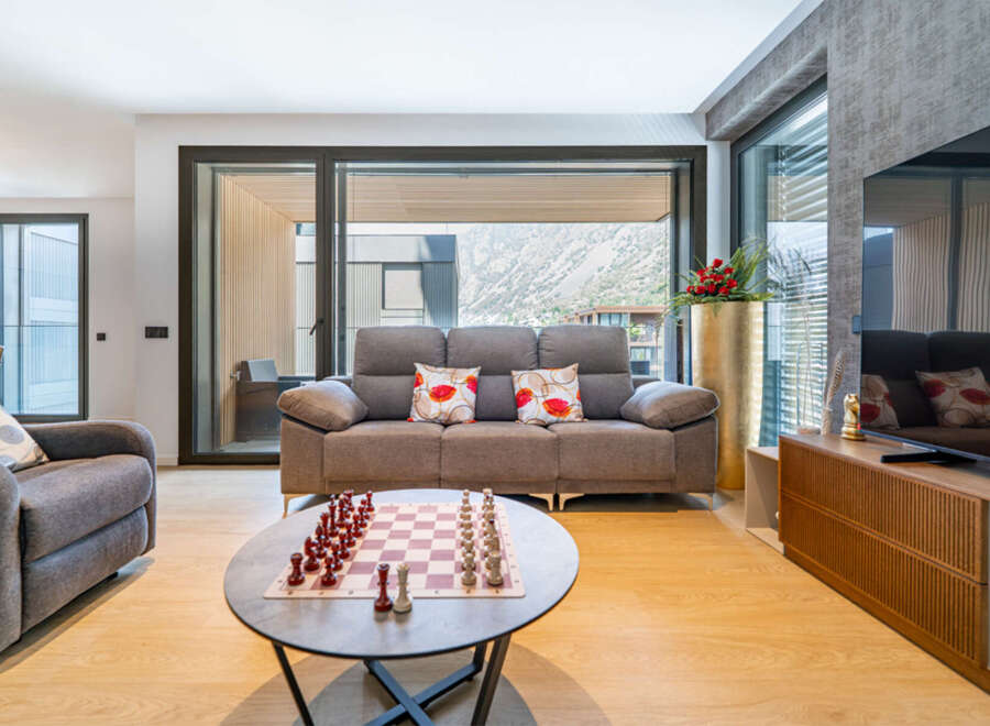 Experience modern living in this stylish apartment, featuring a spacious living area with a comfortable sofa and a large window offering scenic views.