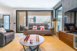 Experience modern living in this stylish apartment, featuring a spacious living area with a comfortable sofa and a large window offering scenic views.