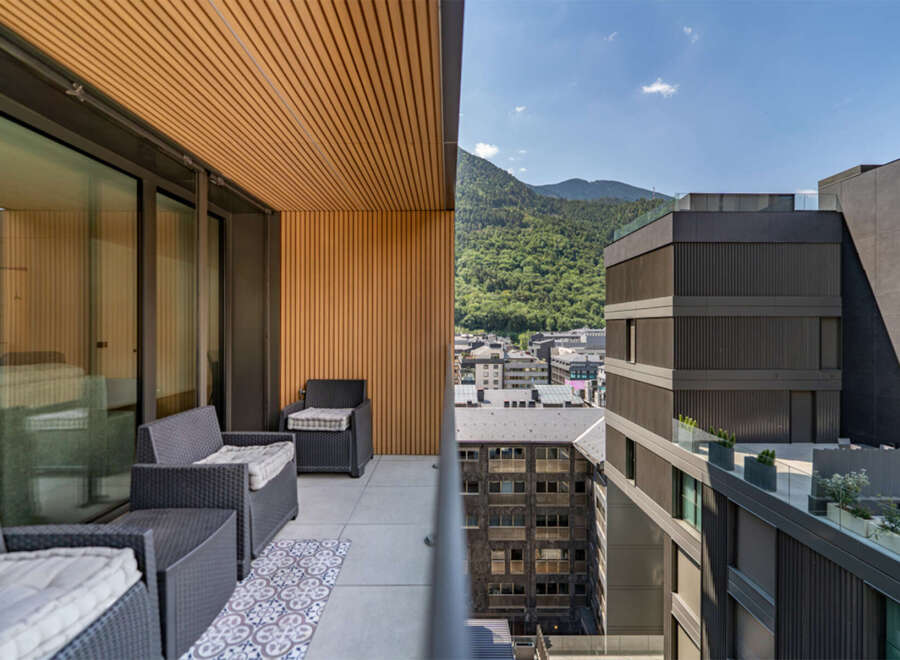 Experience breathtaking mountain views from this modern balcony, featuring comfortable outdoor seating and a stylish patterned rug.